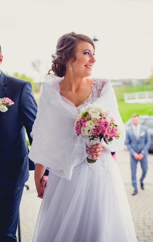 elegancka gorsetowa suknia z bogato zdobioną koronką z etolą ślubną